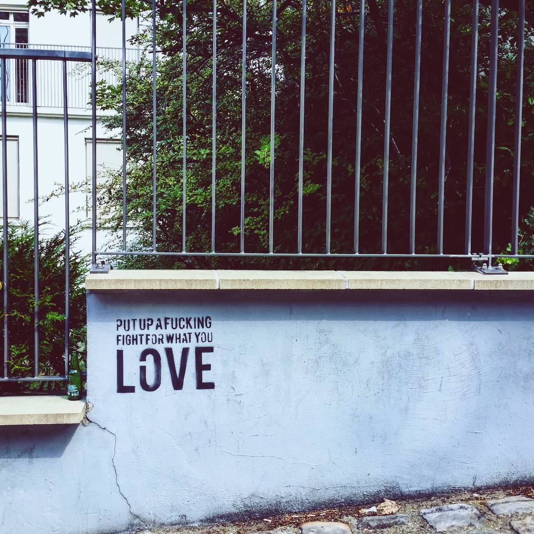 A wall with "put up a fucking fight for what you love" stenciled on.
